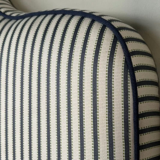 Headboard dressed in Agathe Stripe showing details and the tone-in-tone piping.