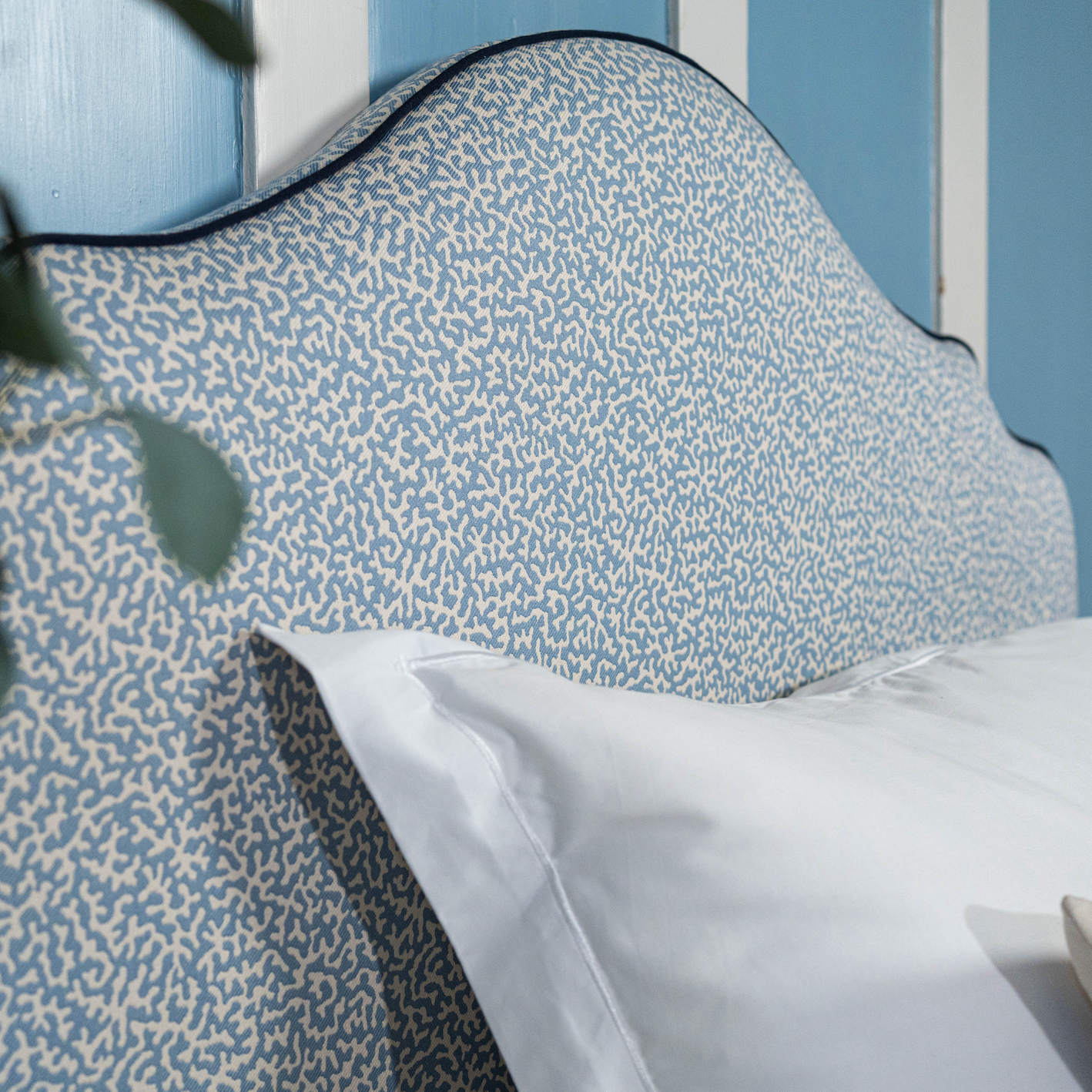 Headboard upholstered in Apolline from Colefax and Fowler with a coral motif, and dark blue piping from Houles Paris.
Sengegavl med korallmotiv. 