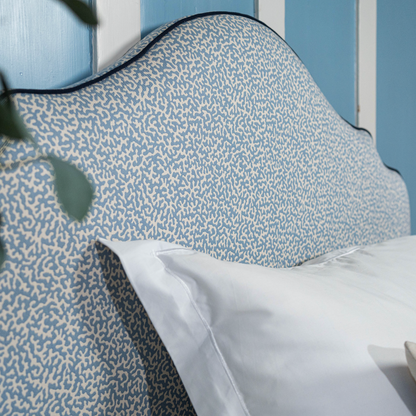 Headboard upholstered in Apolline from Colefax and Fowler with a coral motif, and dark blue piping from Houles Paris.
Sengegavl med korallmotiv. 