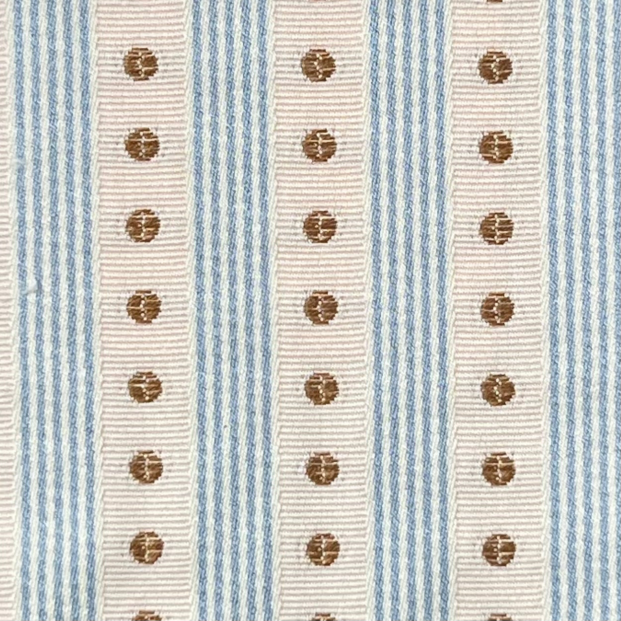 Close-up of a fabric with blue and beige stripes and brown circular patterns.