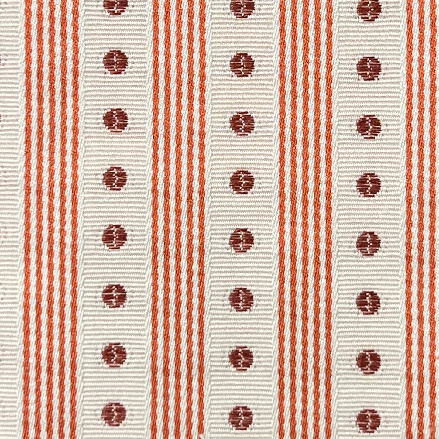 Close-up of a fabric with red stripes and circular patterns on a white background